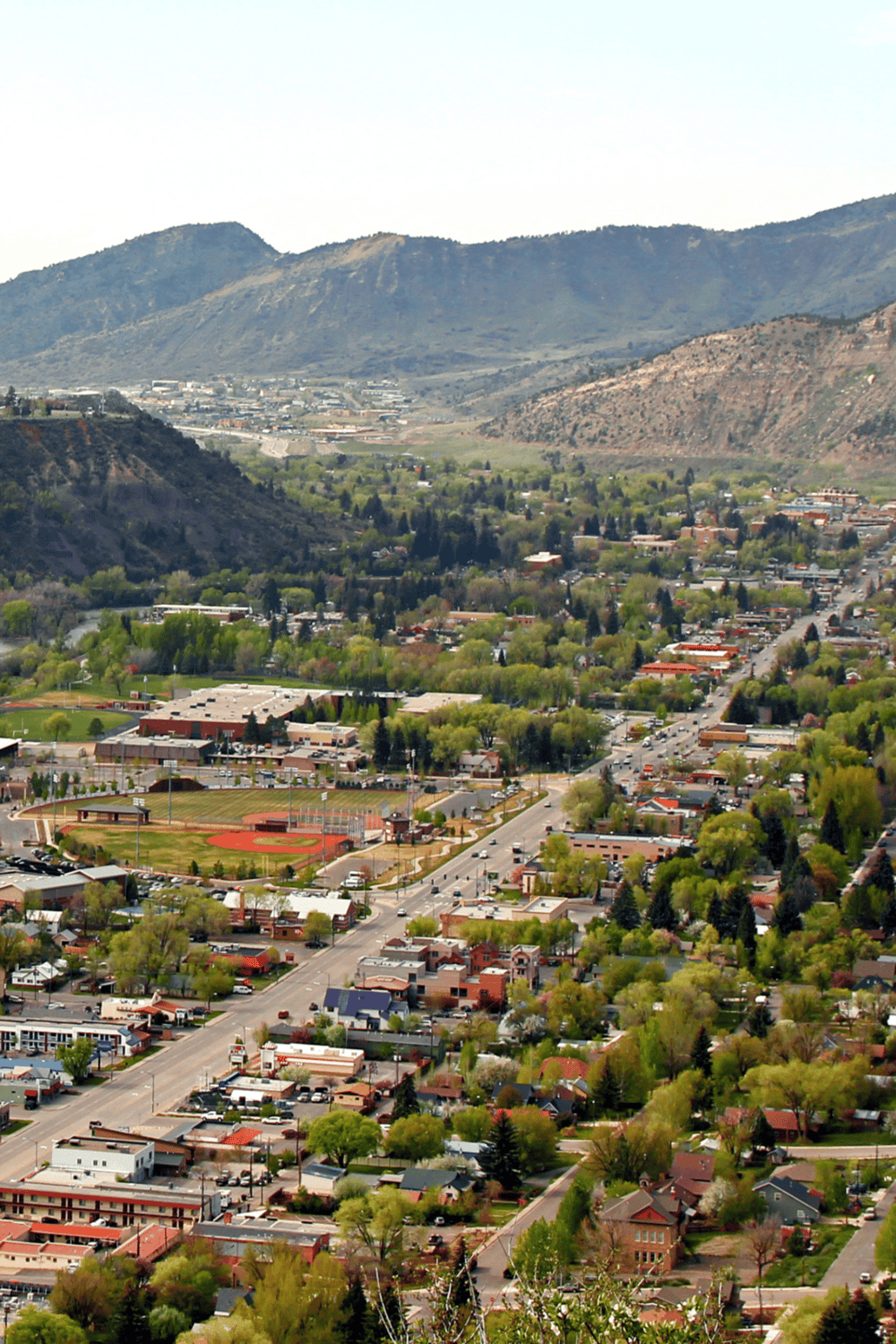 Scenic aerial view of a town set amidst rolling mountains, showcasing community spaces and lush greenery.