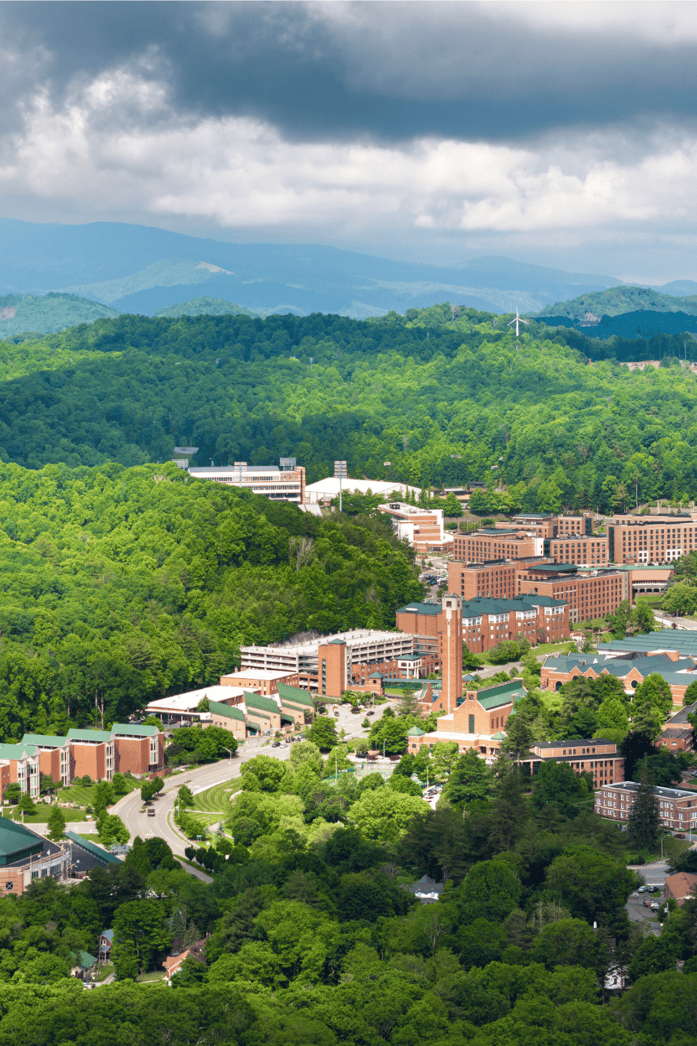 Aerial view of Quest for Directions campus surrounded by lush green mountains and trees.