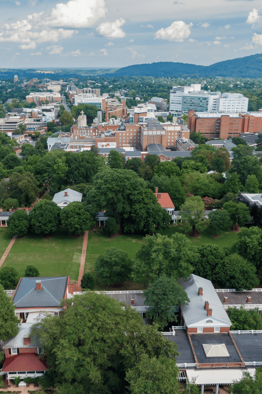 Vibrant cityscape with lush green parks, towering buildings, and scenic mountain views in the background.