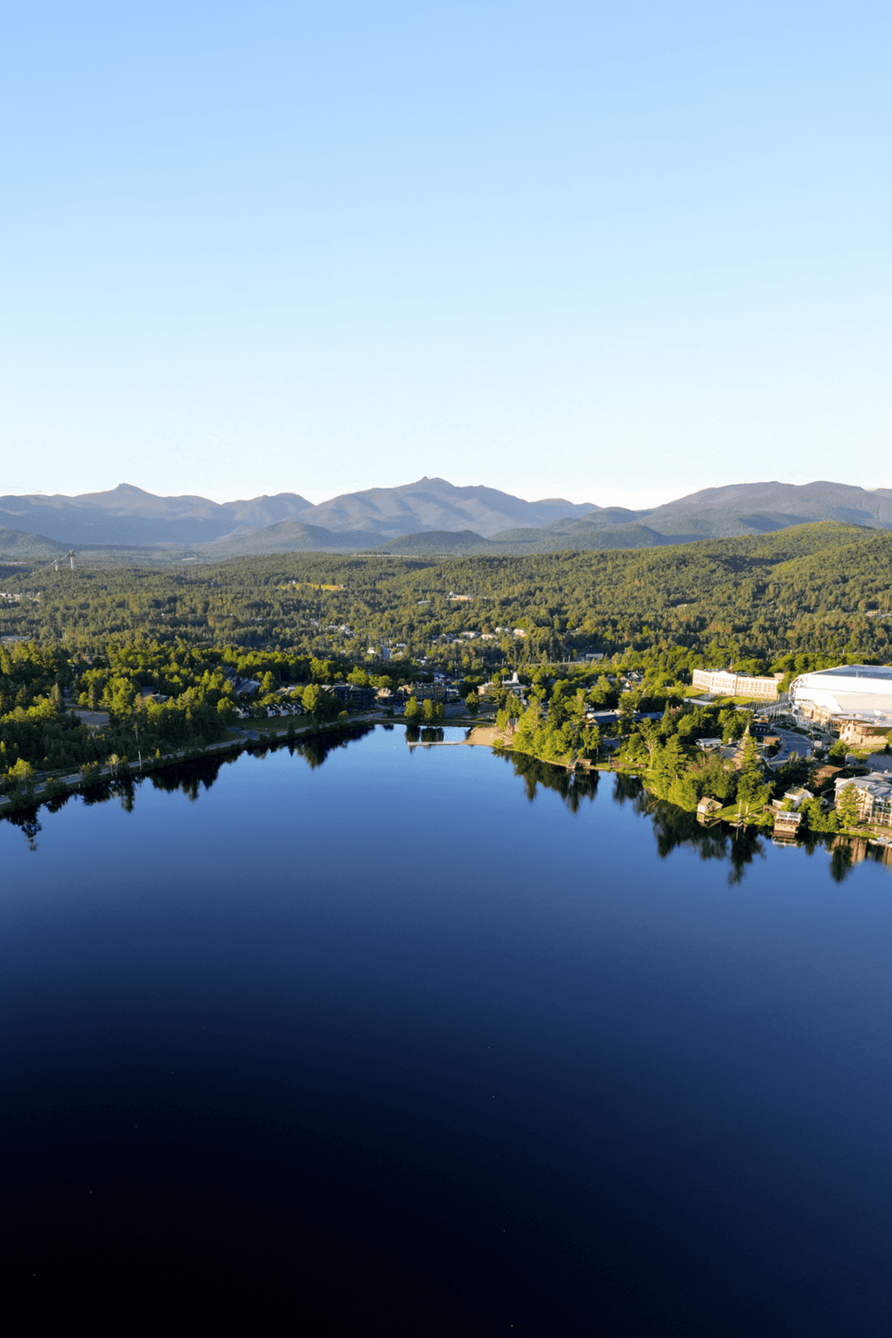 Serene mountain lake surrounded by lush forest and scenic town views, perfect for outdoor adventures.