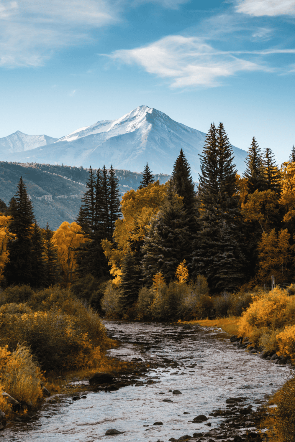 Snow-capped mountain overlooking lush forest and river in autumn, scenic landscape, QuestForDirections travel destination.