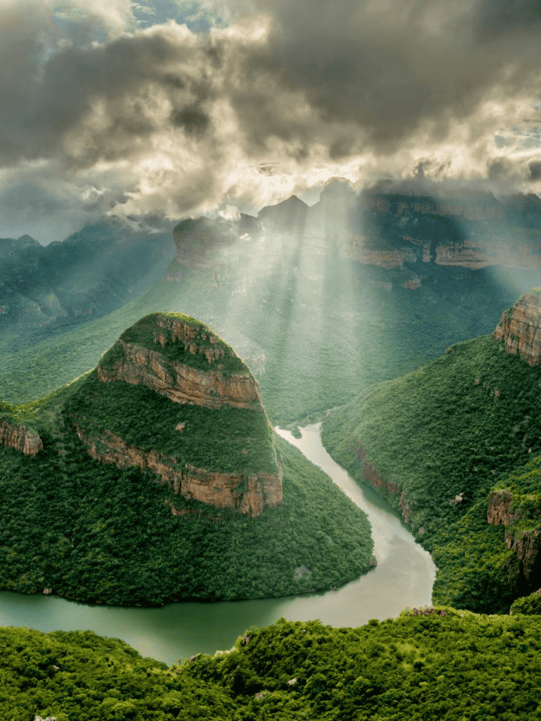 Vivid canyon landscape with winding river, lush greenery, and dramatic clouded sky, perfect for adventure and nature travel inspiration.
