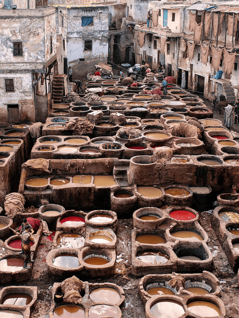 Colorful traditional leather dyeing pits in Morocco for artisanal leather production, bustling with workers.