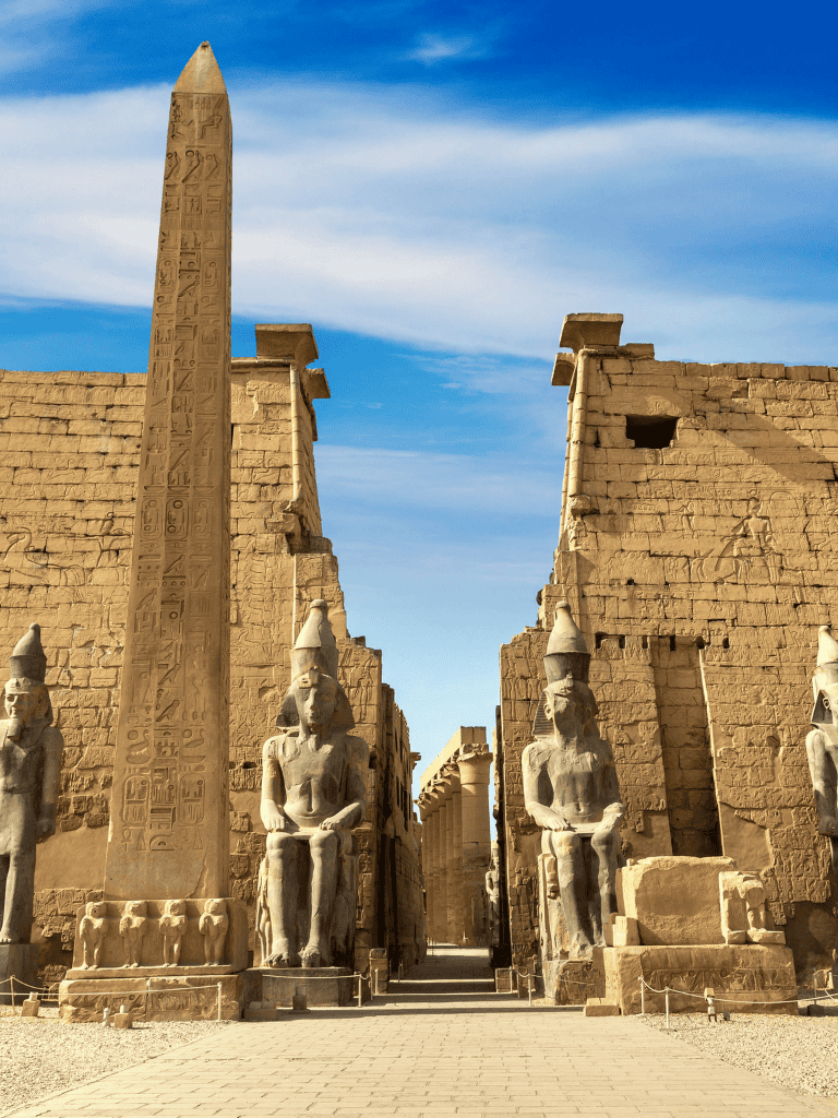 Ancient Egyptian obelisk and statues at historical site, Nile River Egypt, travel guide.
