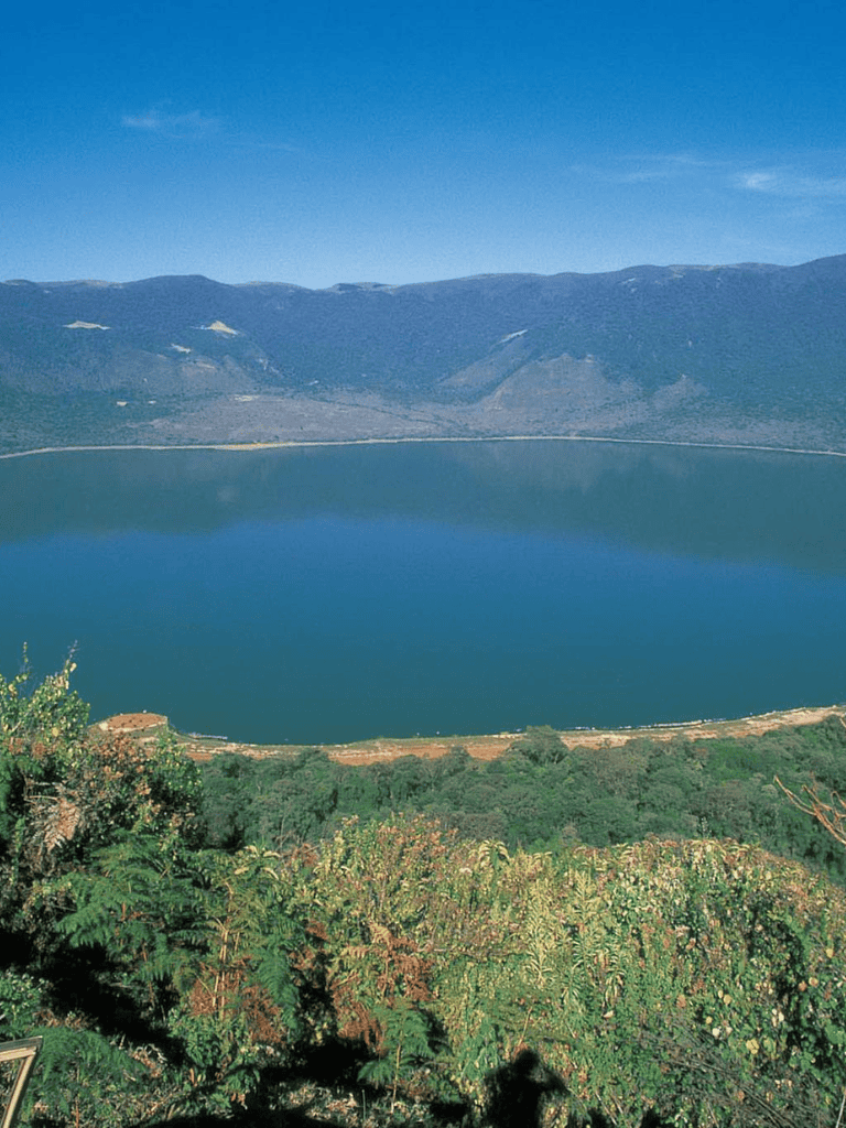 Serene mountain lake surrounded by lush greenery and towering mountains, perfect for outdoor adventures and nature exploration.