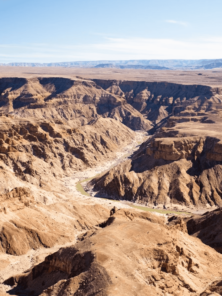 Breathtaking canyon landscape with rugged cliffs and flowing river in a desert environment.