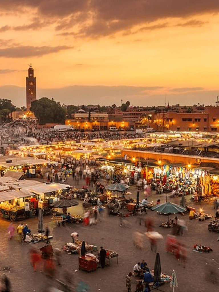 Vibrant market square at sunset in Morocco with bustling vendors and lively crowd.