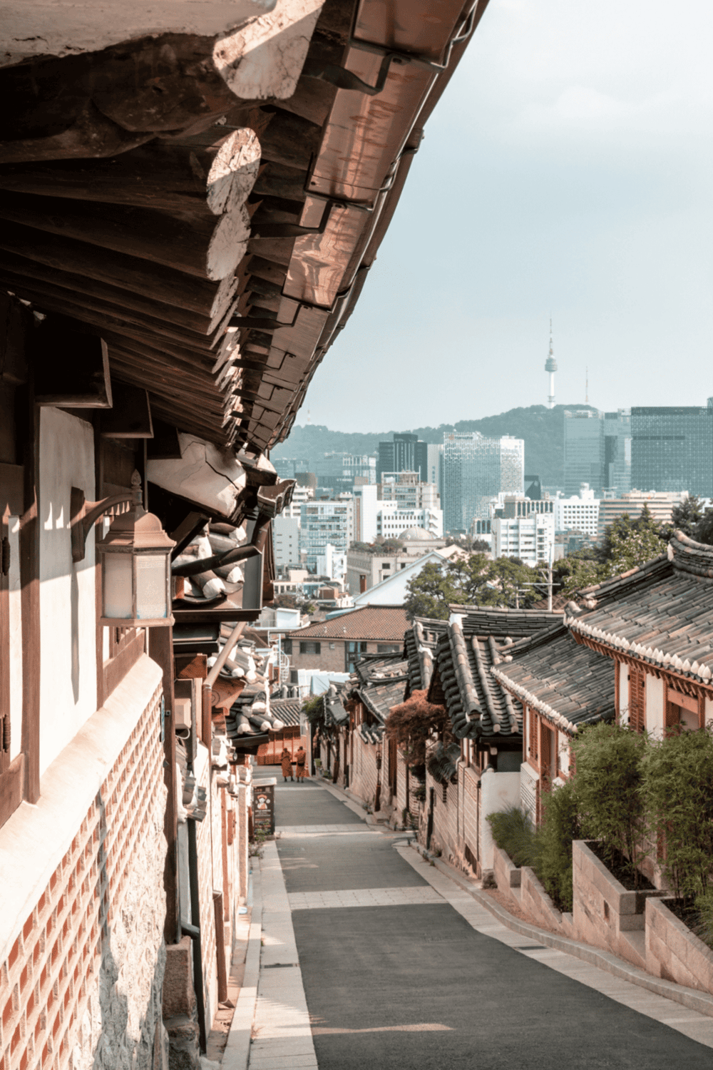Traditional Korean Hanok village with modern Seoul skyline in background, cultural heritage, sightseeing, travel destination.