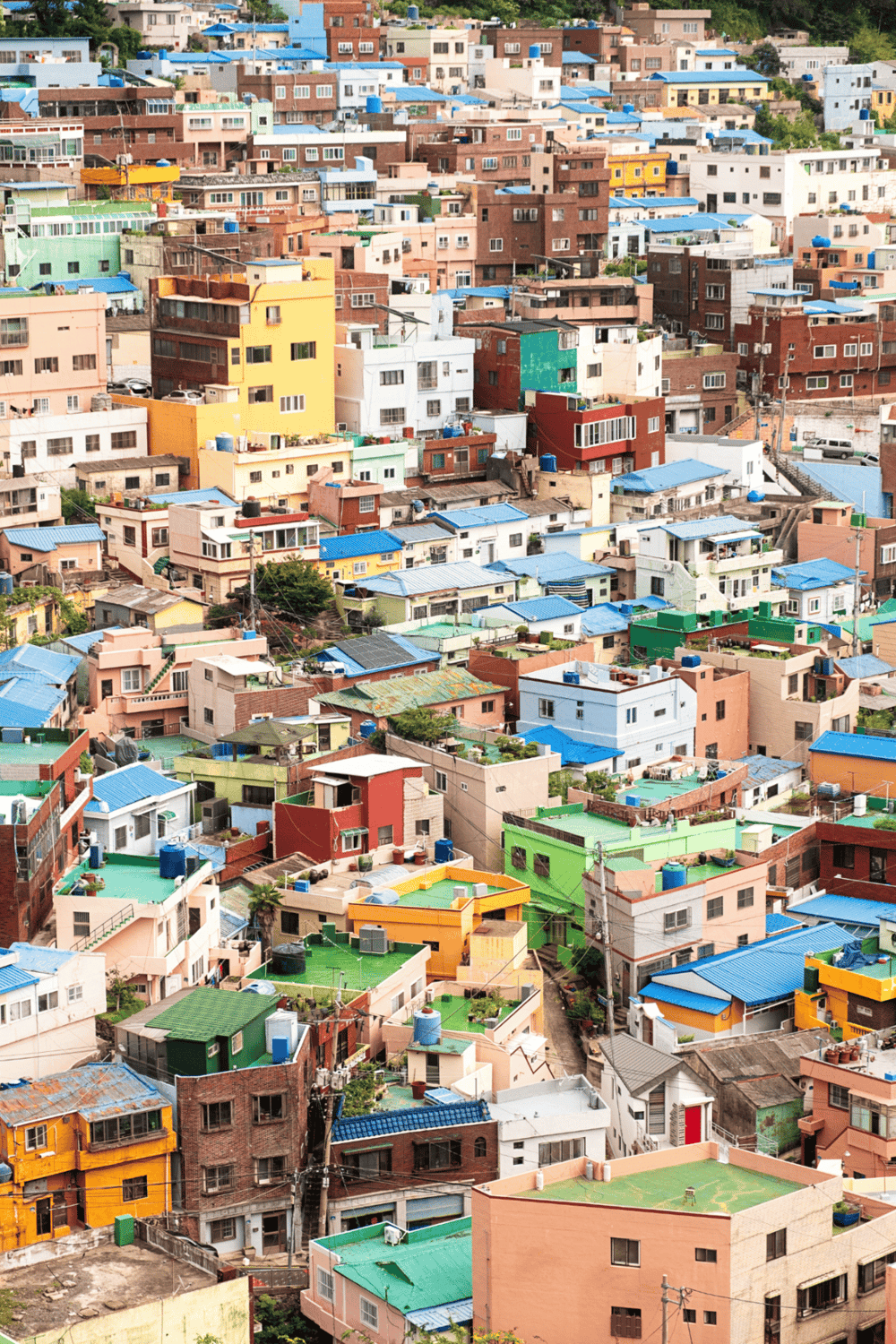 Colorful hillside neighborhood with vibrant houses and blue roofs, illustrating urban diversity.