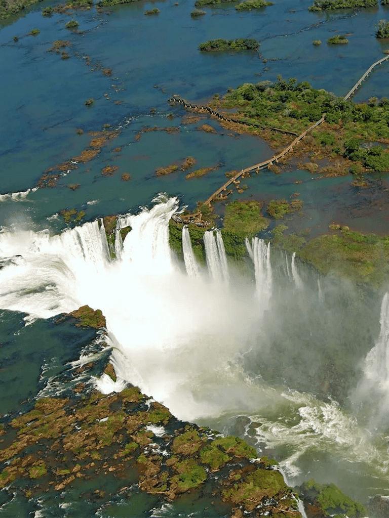 Vast waterfall and lush greenery with walking paths at Iguazu Falls, South America.