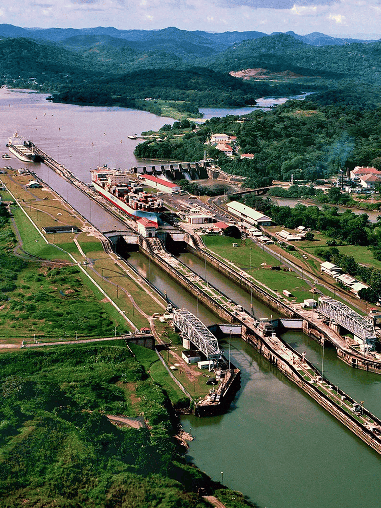 Locks and dams on a river near lush green mountains, with boats navigating through canal waterways.