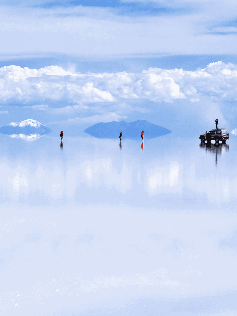 Surreal salt flats with hikers and a vehicle against a mountain backdrop, like the Salar de Uyuni in Bolivia.