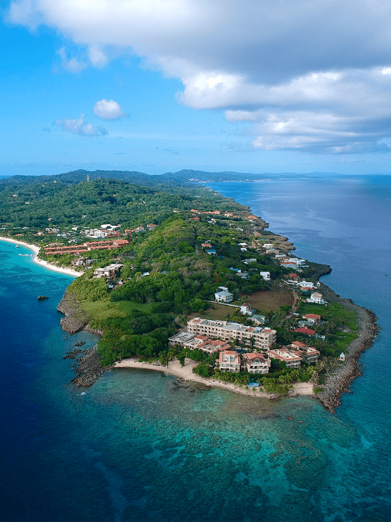 Breathtaking aerial view of a lush tropical island with luxury resorts and pristine beaches.