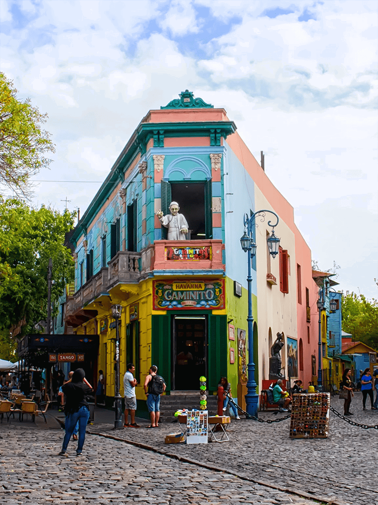 Colorful colonial building in Havana, vibrant street scene with tourists and street vendors.
