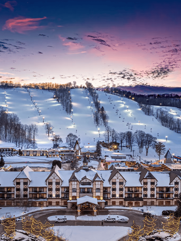 Luxury ski resort in snow-covered mountains during sunset.