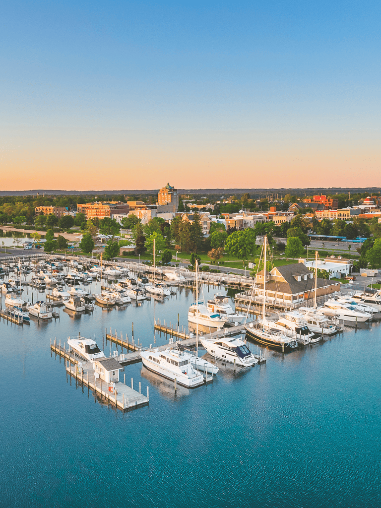 Marina with boats and city skyline at sunset, showcasing scenic waterfront and popular travel destination.