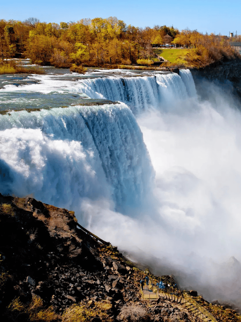 Majestic Niagara Falls during fall with vibrant foliage and cascading water.