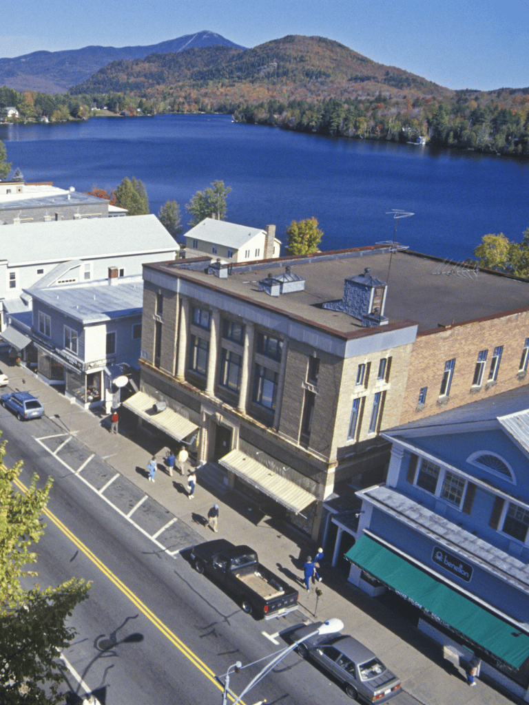 Overlooking a charming town by a serene lake surrounded by mountains, showcasing local businesses and scenic views.
