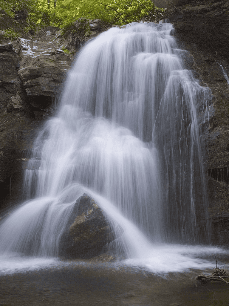 Tranquil waterfall in lush forest scene, cascading over rocks in a natural landscape.