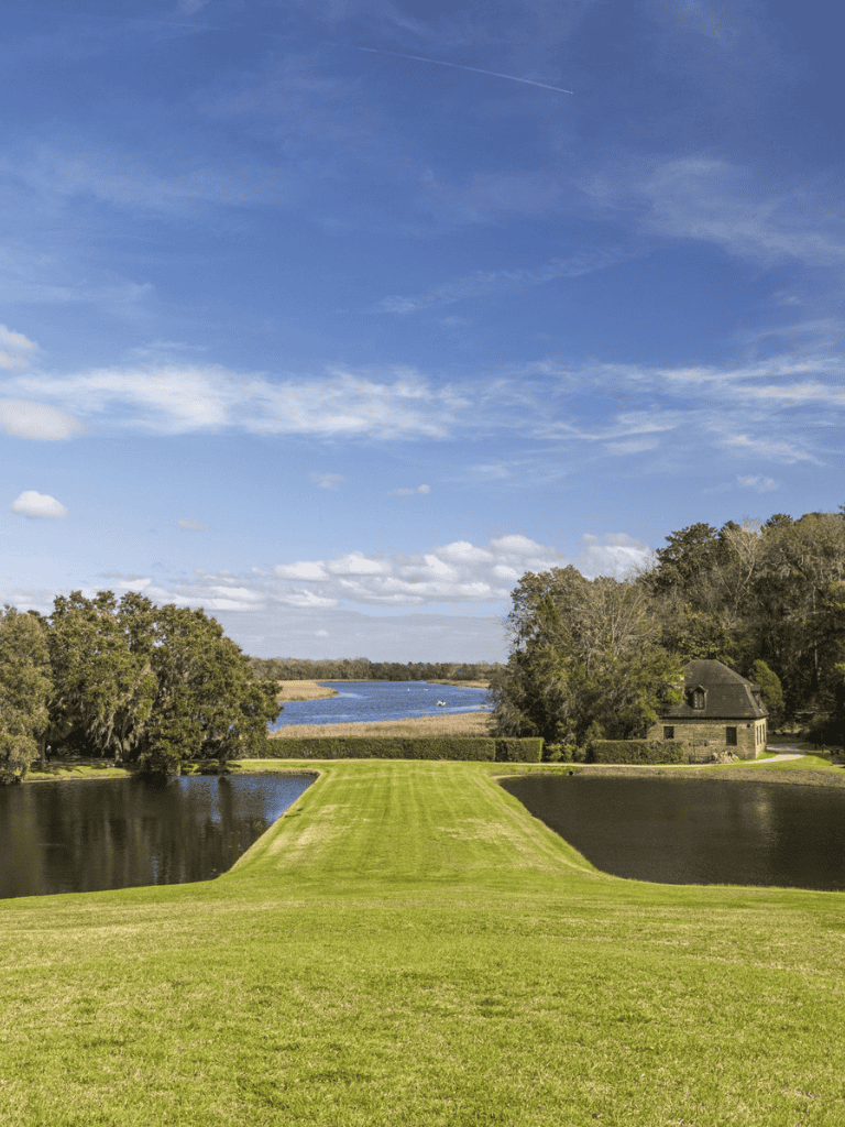 Serene scenic view of QuestForDirections lakeside property with lush greenery and a historic stone house.