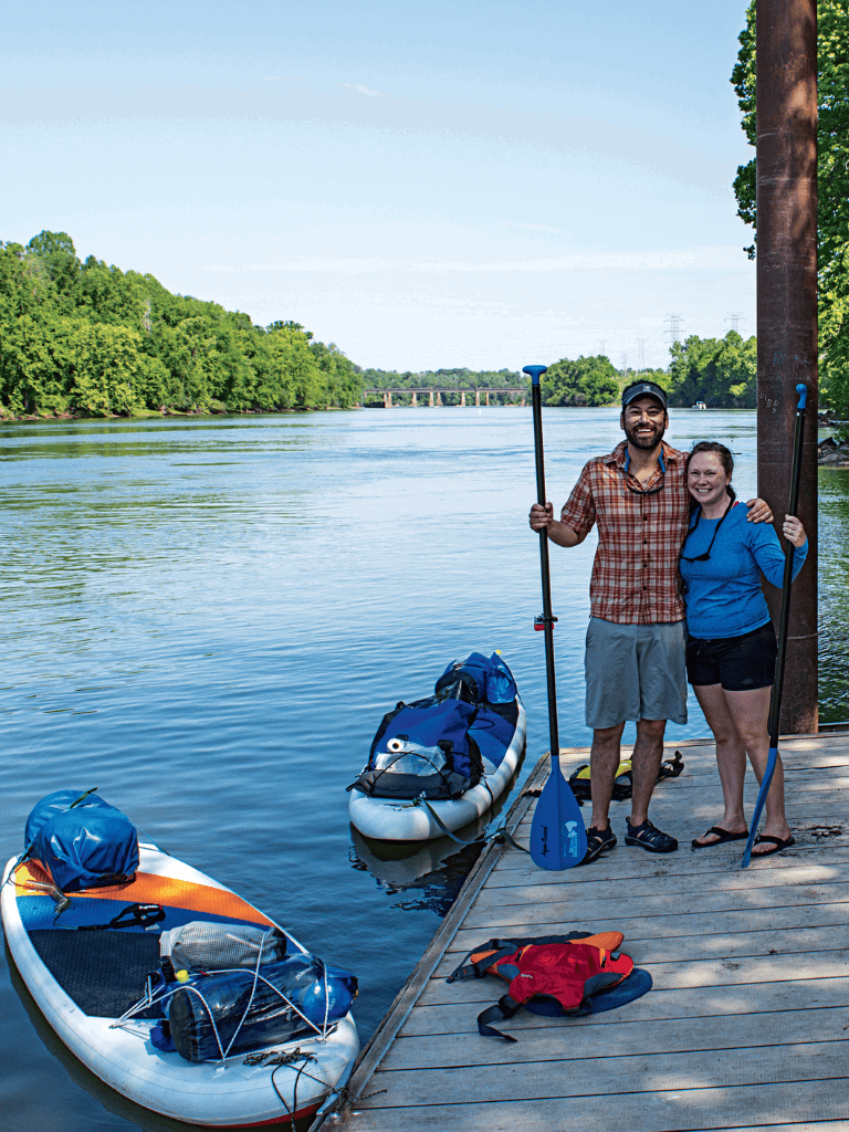 Peaceful paddleboarding by a river with lush green trees, perfect for outdoor adventure lovers.