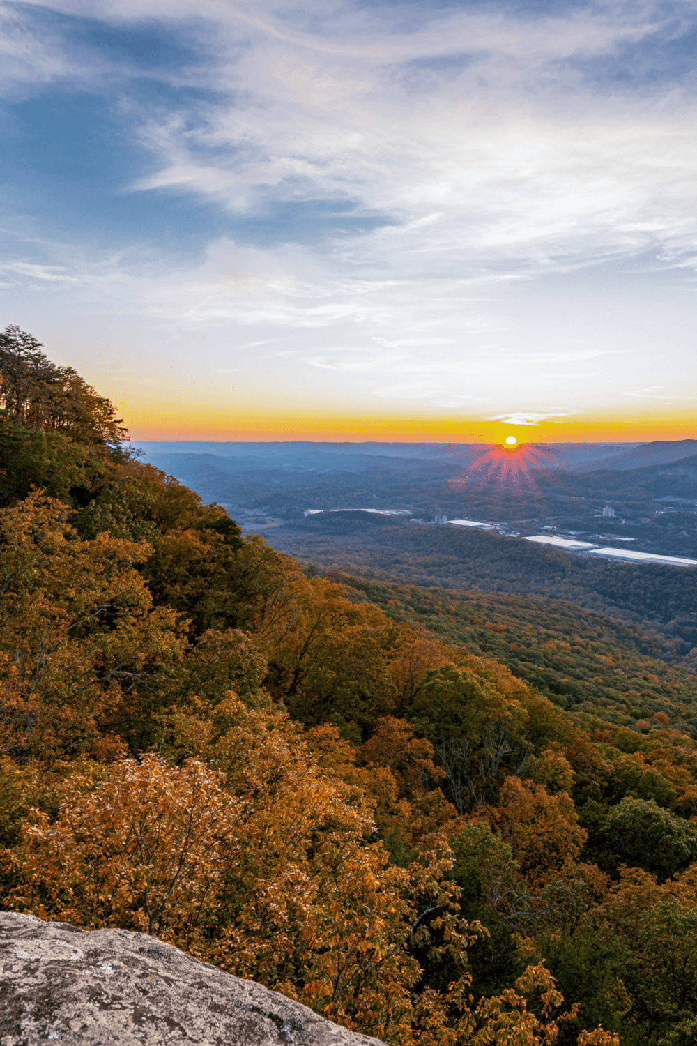 Vibrant fall landscape with mountain view at sunset, showcasing colorful autumn foliage and scenic skyline.