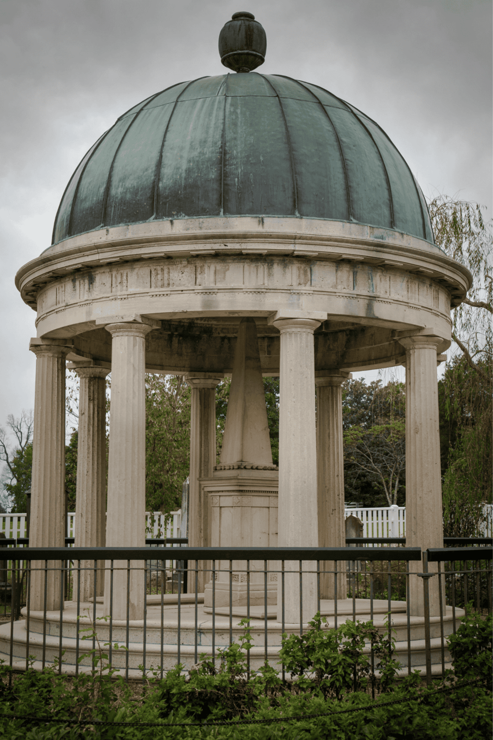 Victorian-style bandstand with domed roof, stone columns, and lush greenery, perfect for events and outdoor gatherings.