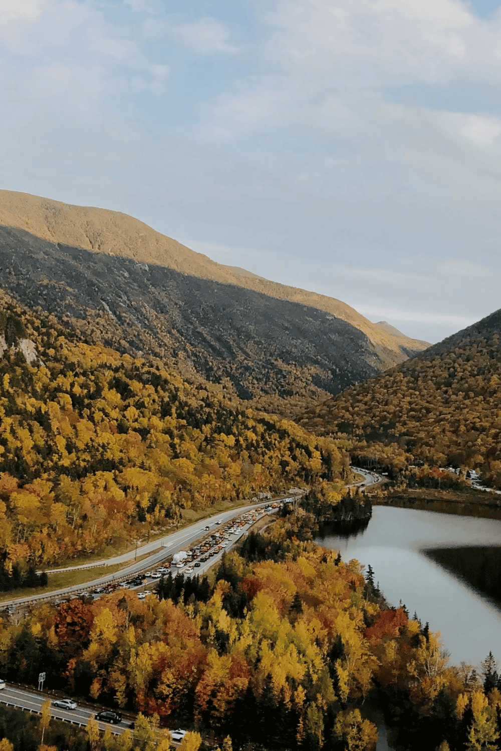 Vibrant autumn landscape with mountains, river, and scenic road, showcasing nature and travel inspiration.