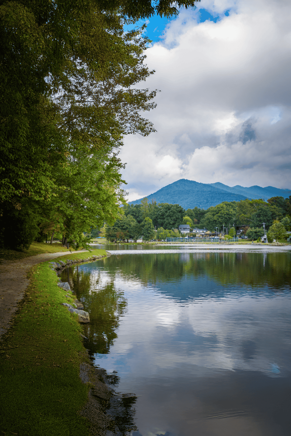 Serene lake with lush trees, mountain views, and a peaceful park setting for outdoor recreation.
