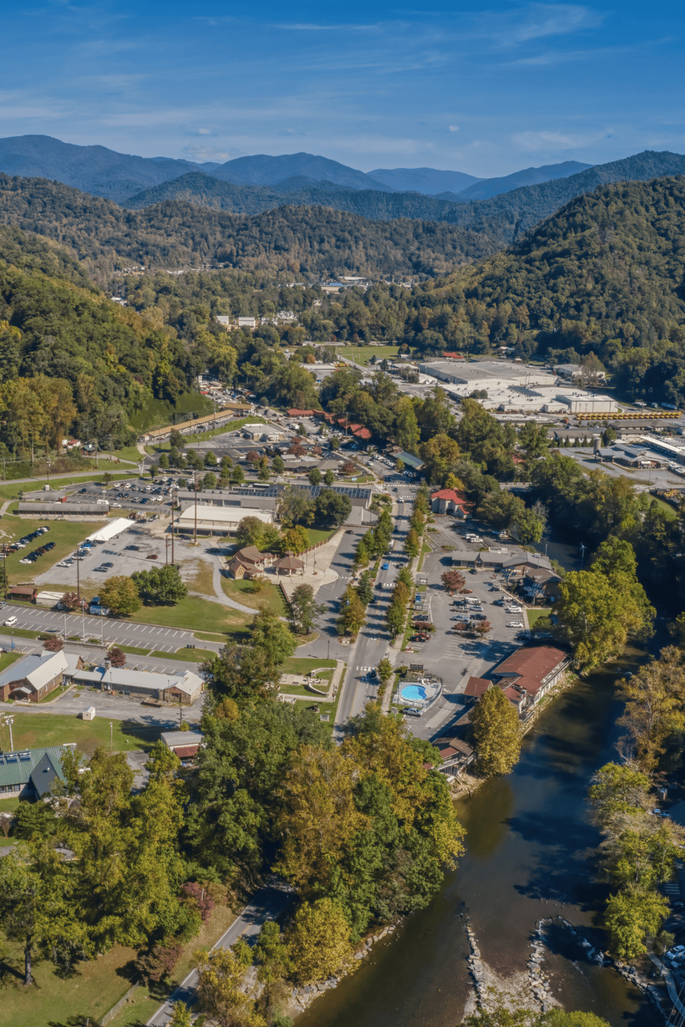 Aerial view of a scenic mountain town with commercial areas and lush greenery.