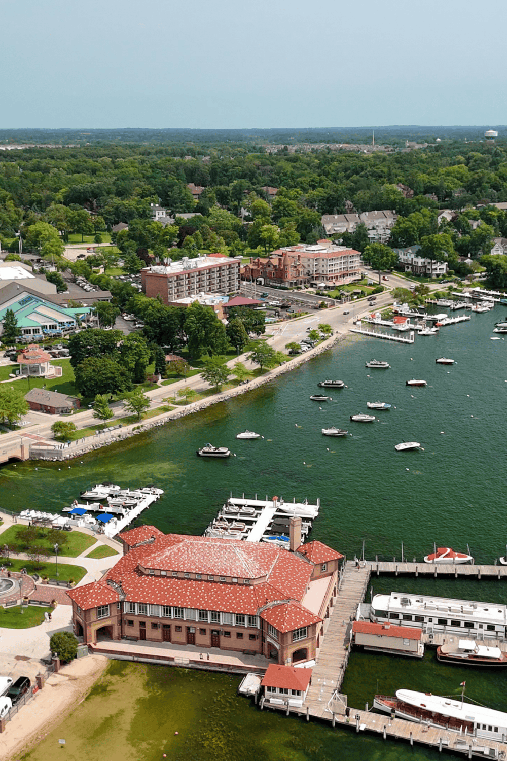 Aerial view of a scenic waterfront with boats, lush greenery, and a charming lakeside town.