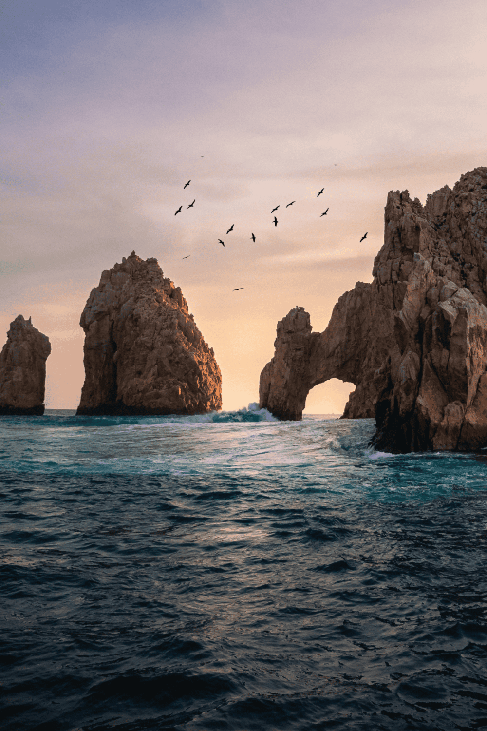 Breathtaking coastal cliffs with natural rock arches at sunset, perfect for travel and adventure photography.