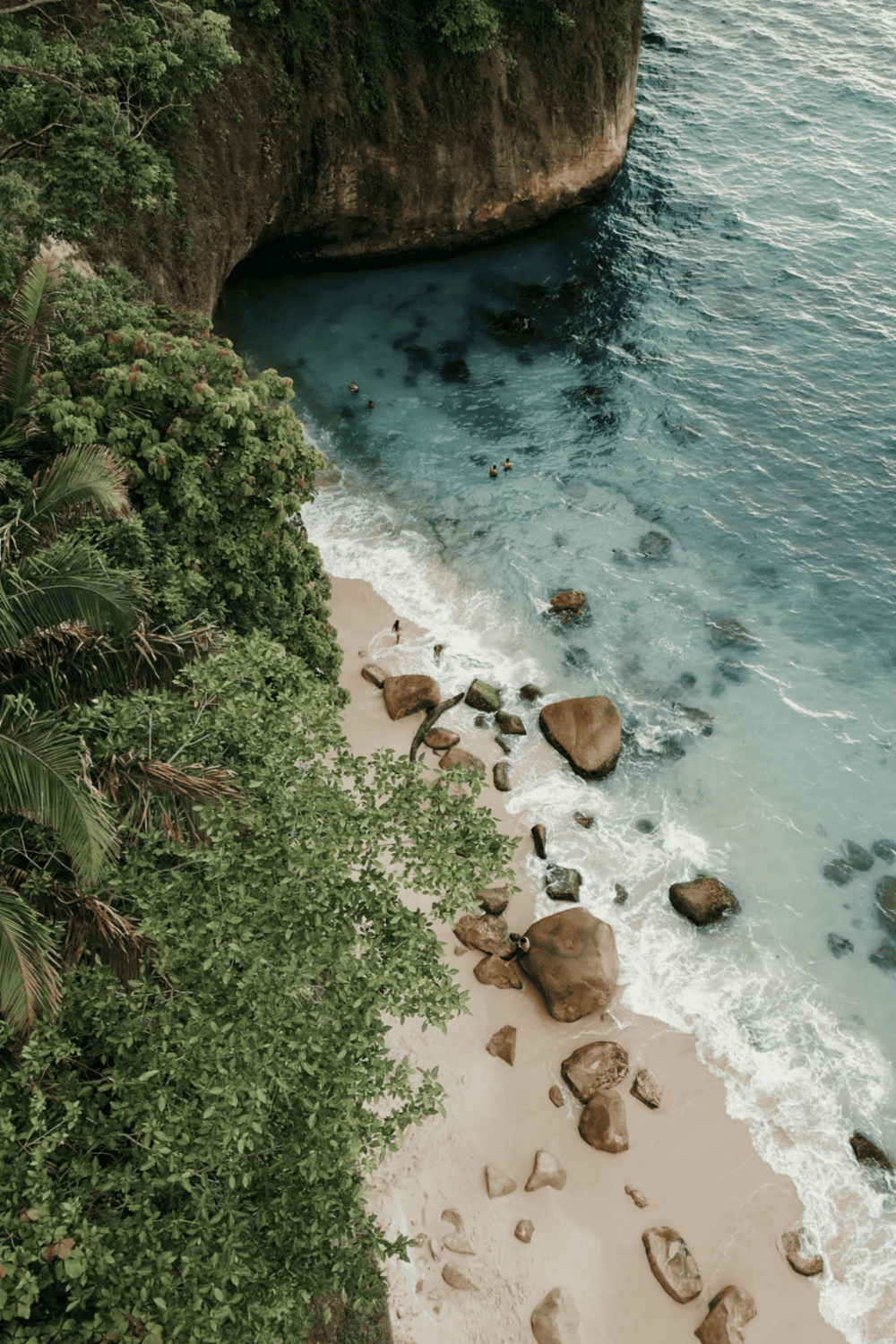 Secluded tropical beach with rocky shoreline and lush greenery, perfect for exploration.