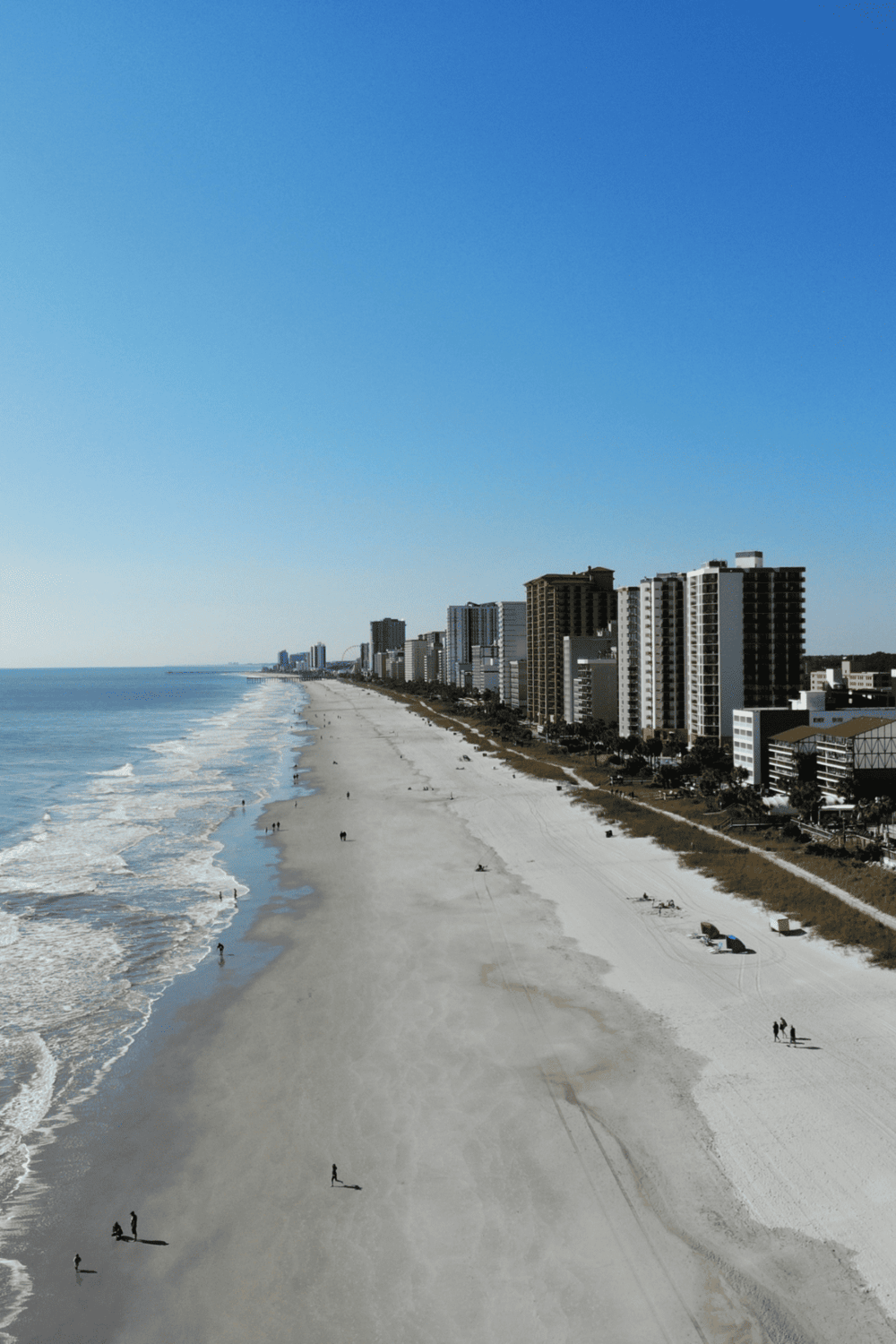 Long beach coastline with modern city skyline, sunny sky, and sandy shores, perfect for exploring directions.