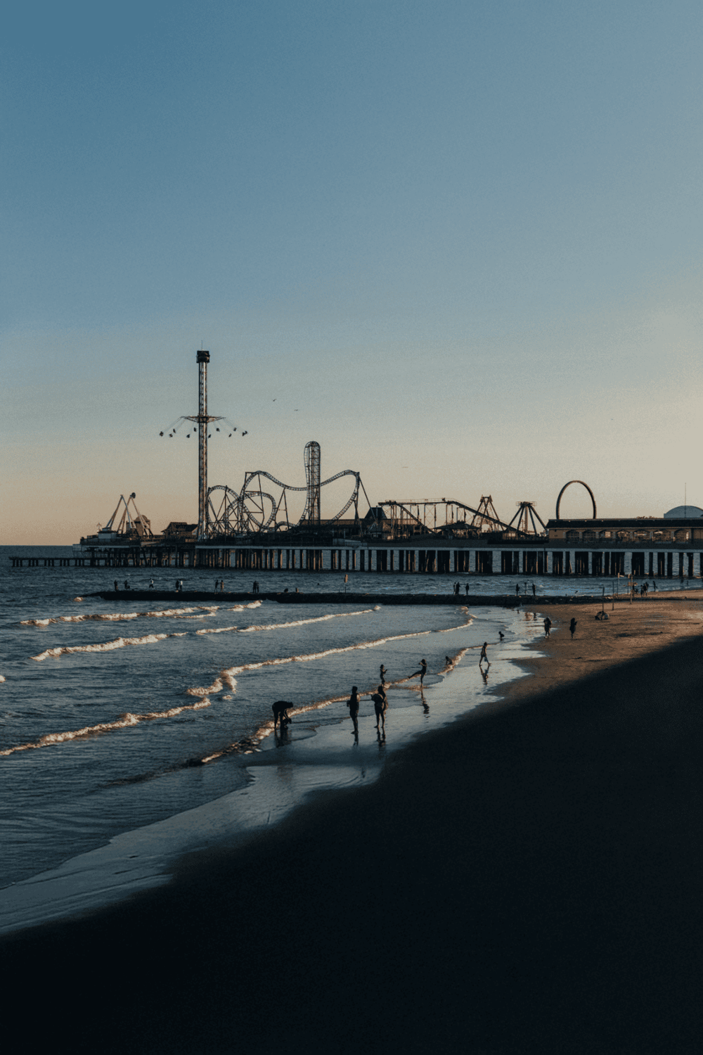 Amusement park pier with rides and ocean view, Cali beach tourism, coastal fun and entertainment destination.
