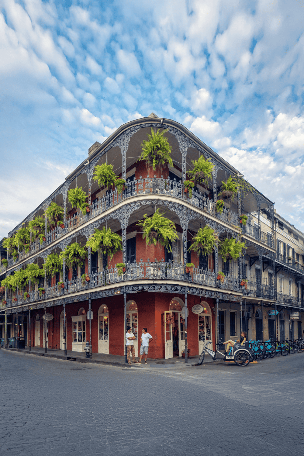 Colorful historic building with lush greenery, corner street view, New Orleans charm, architecture, and vibrant cityscape.