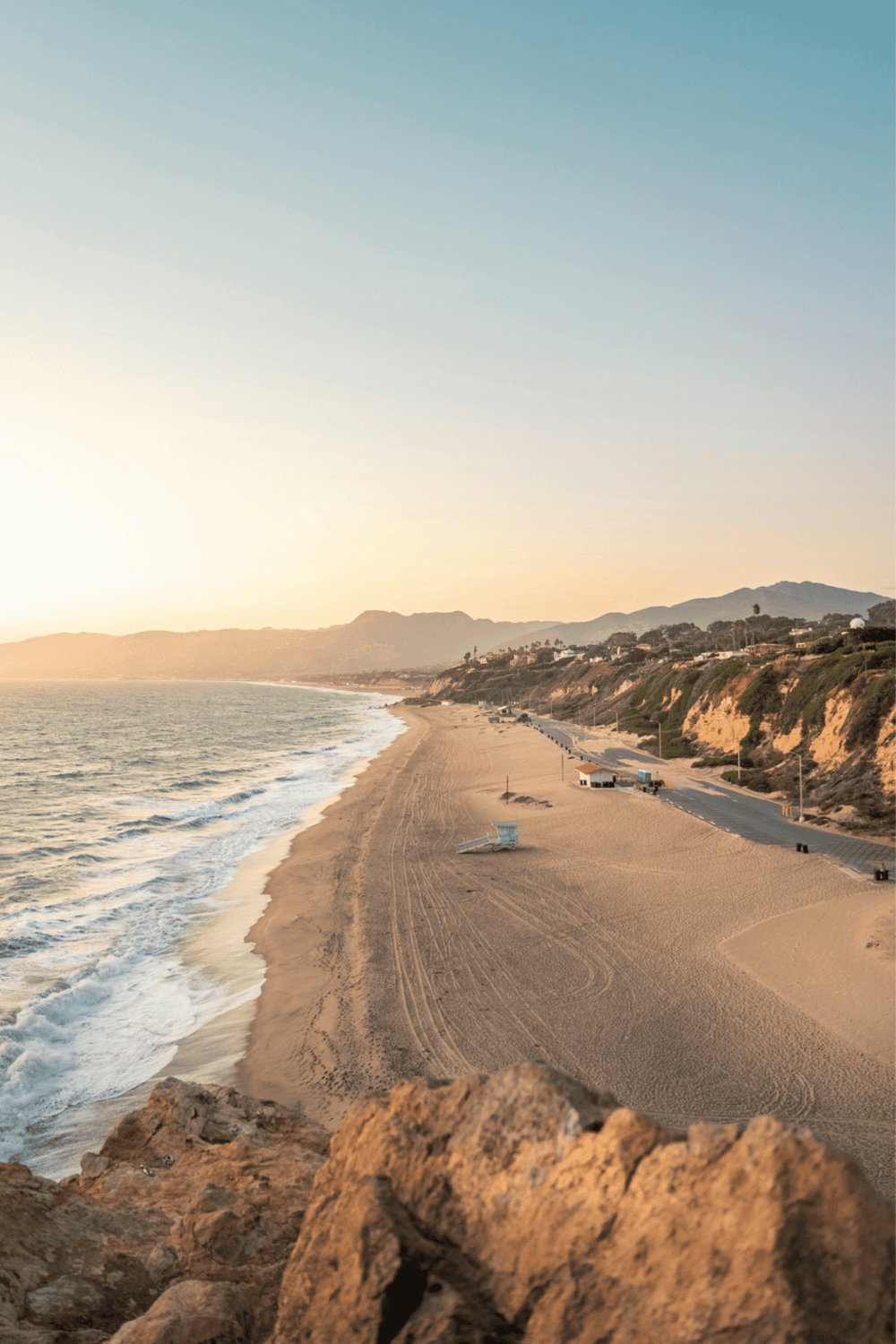 Gentle coastline at sunset with sandy beach and scenic cliffs, perfect for travel and navigation inspiration.
