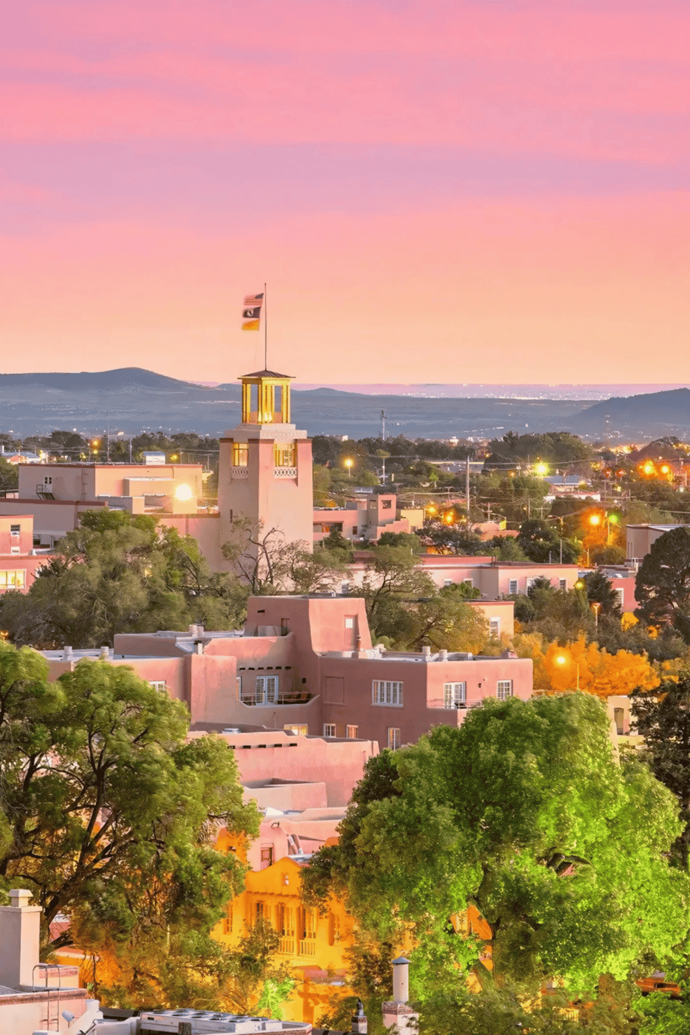 Colorful hillside town with pink and green buildings at sunset, perfect for travel and adventure seekers.