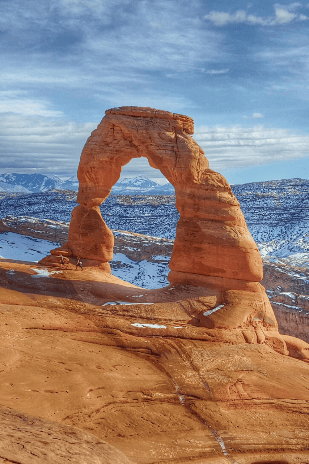 Majestic Delicate Arch in Arches National Park, Utah, with snow-capped mountains in the background.