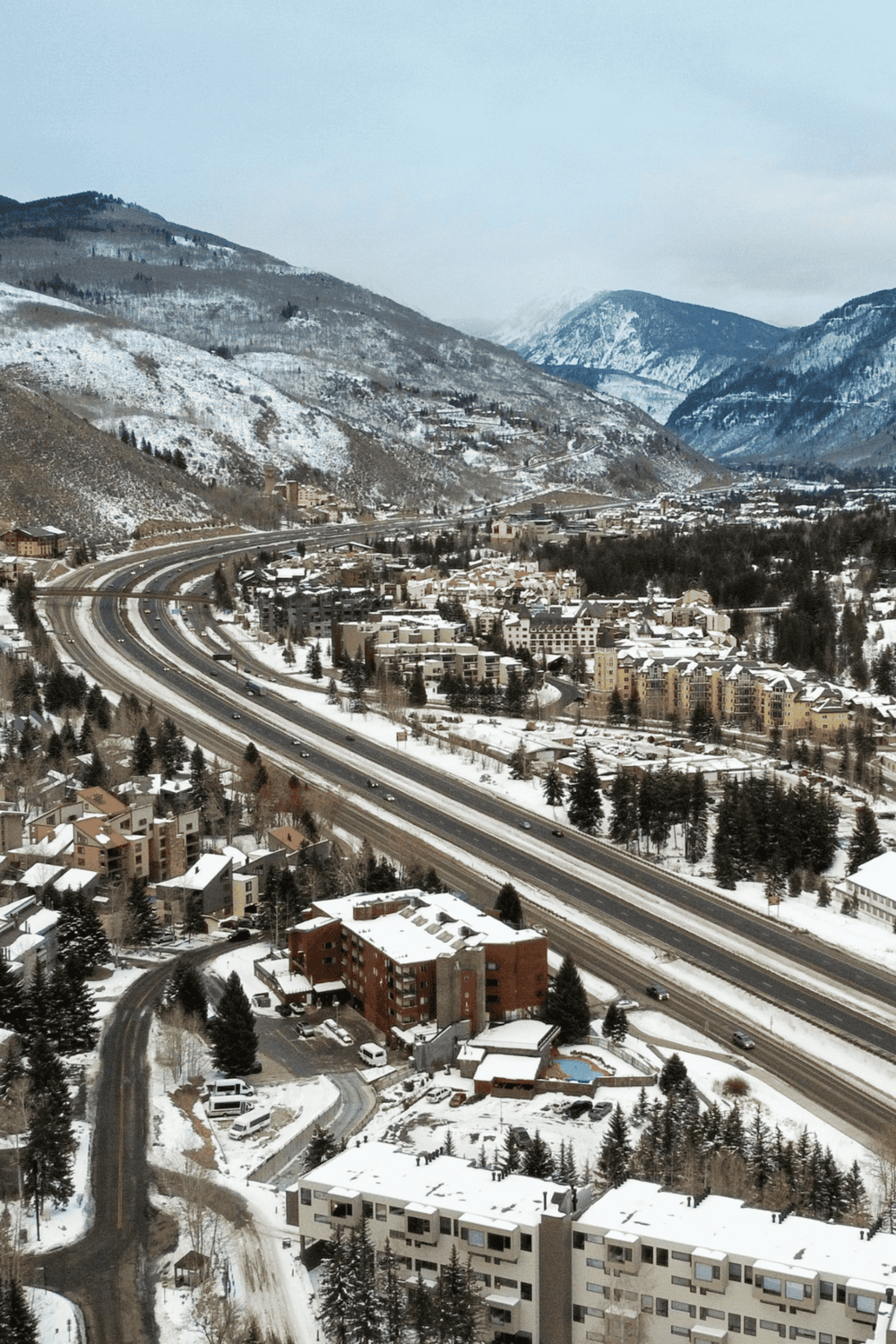 Snowy mountain town with highways, residential buildings, and scenic winter landscape.