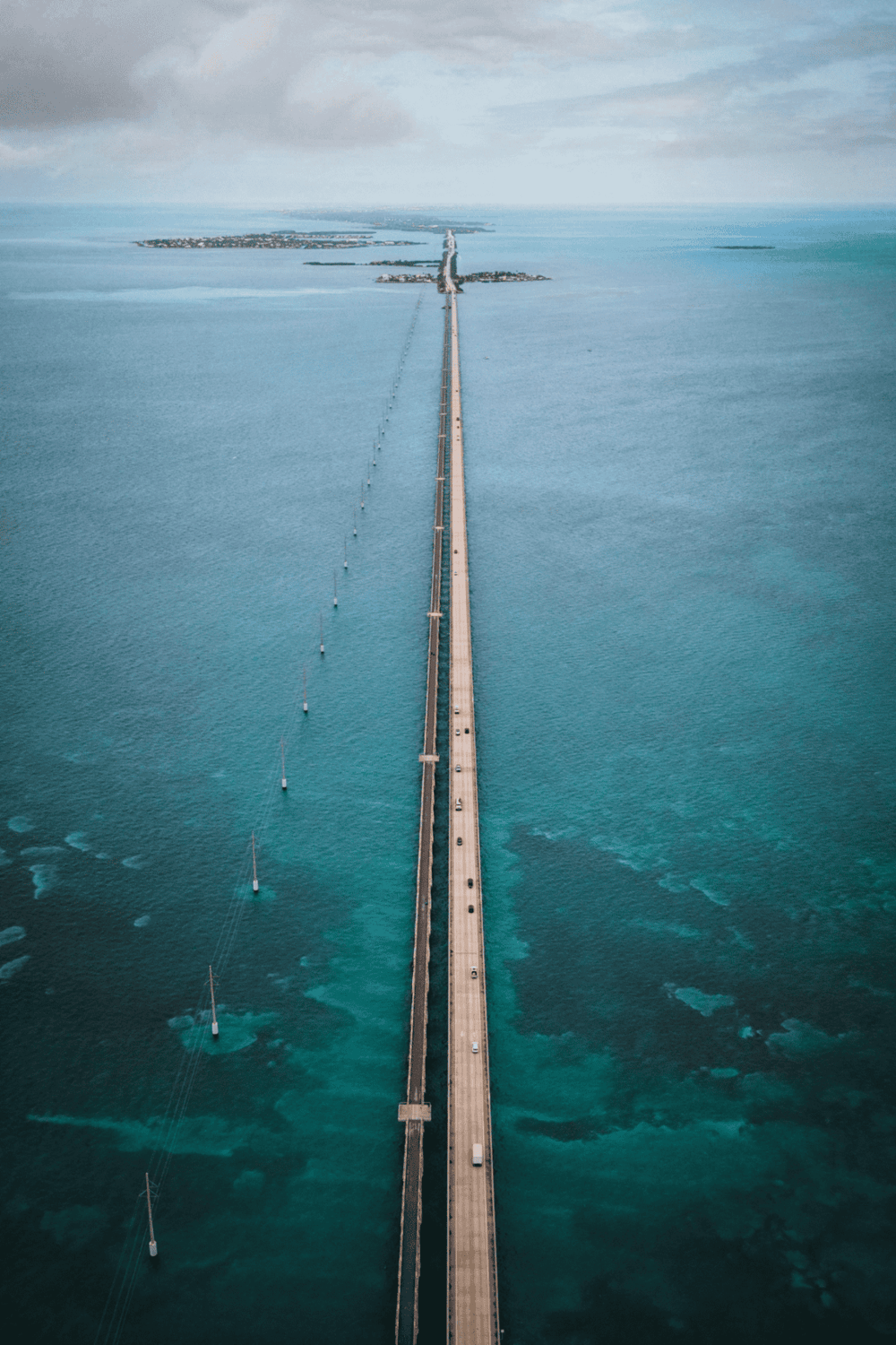 Aerial view of a bridge extending over turquoise waters connecting islands, illustrating scenic transportation routes.