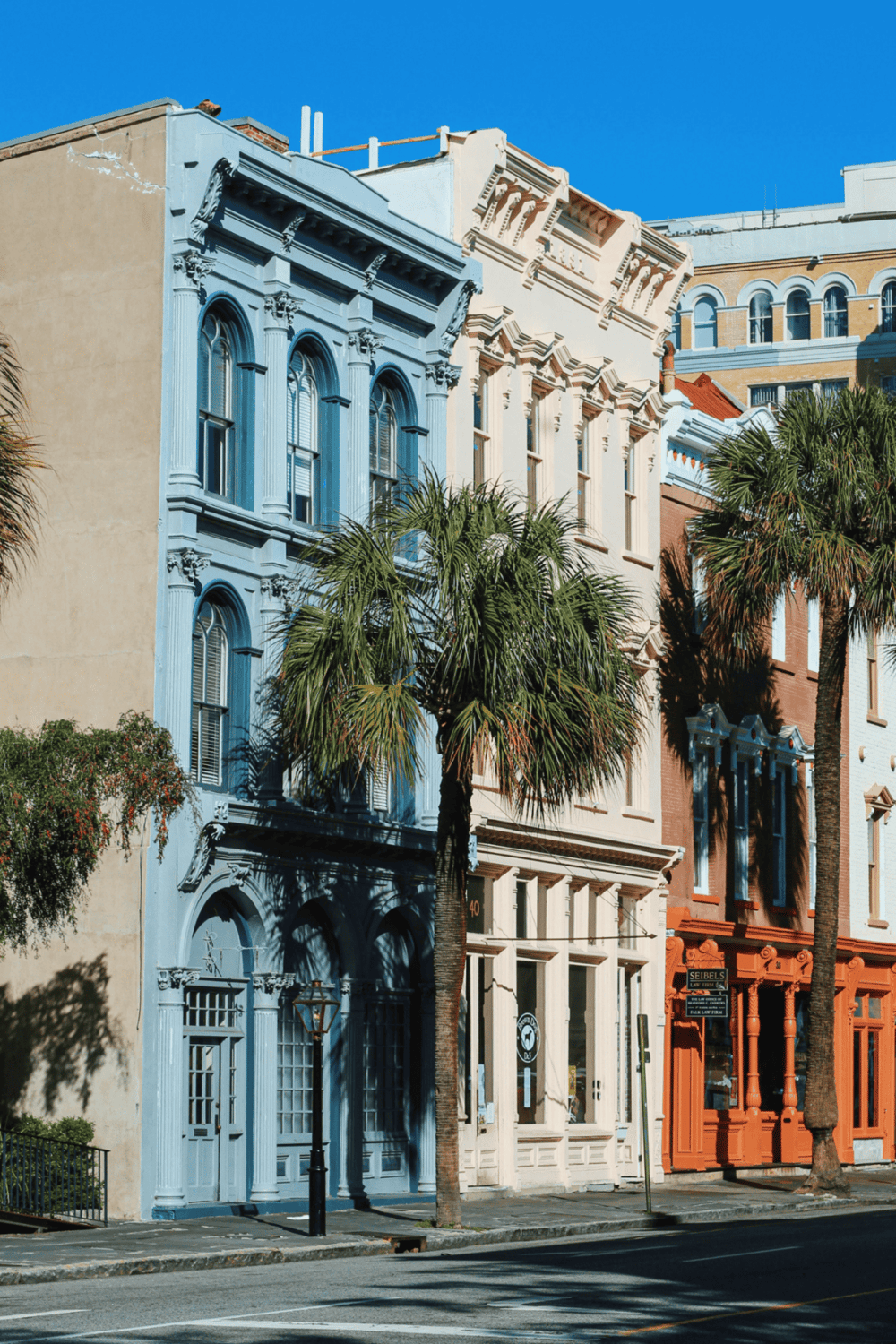 Colorful historic buildings on a sunny street with palm trees in San Francisco.