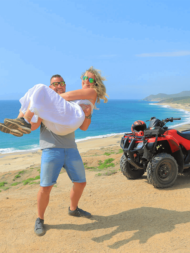 1. Happy couple enjoying coastal view with quad bike and outdoor adventure gear.