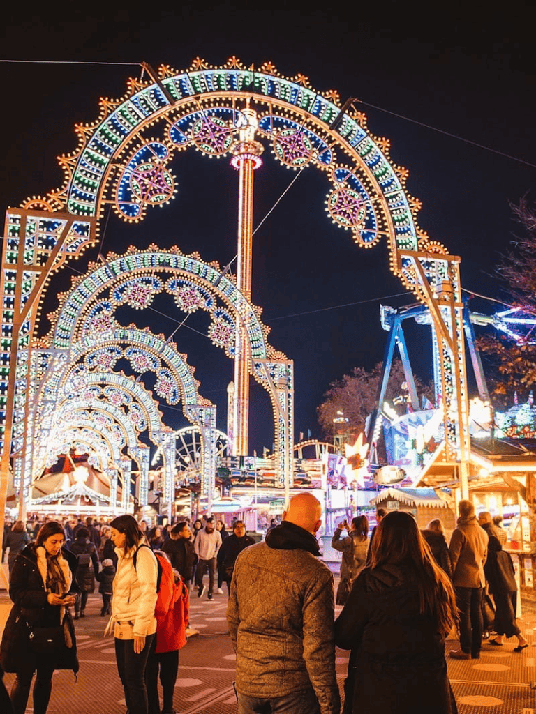 Brightly lit fairground with colorful rides and crowd at night for family entertainment and event visits.