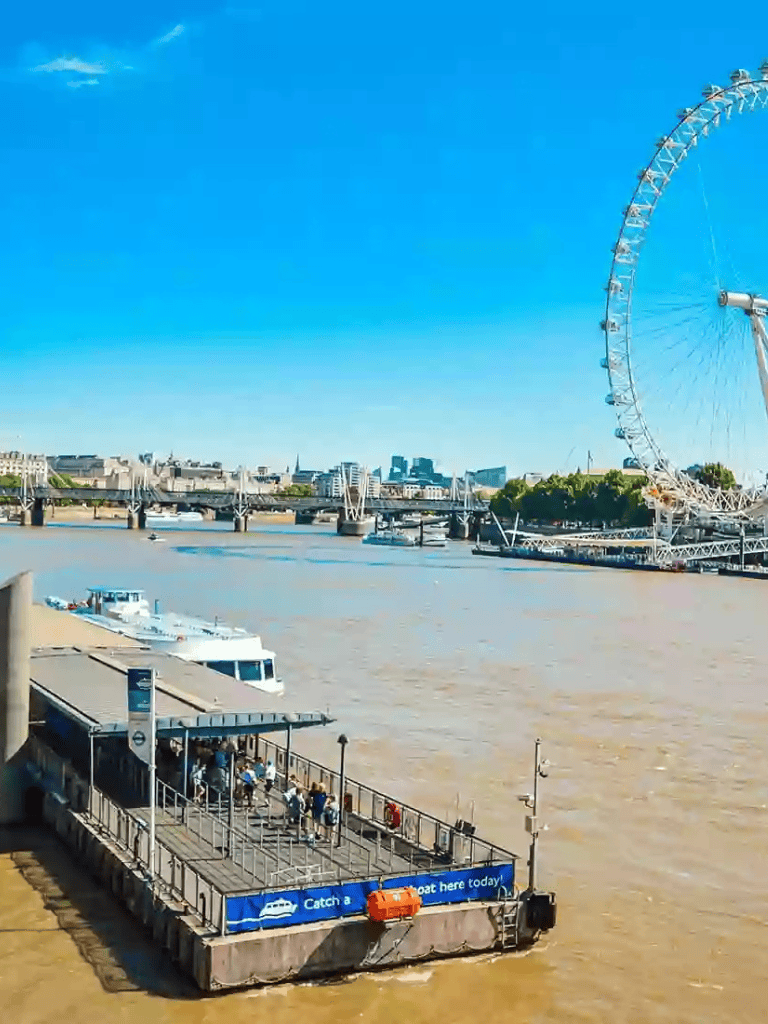 Bright London Thames River scene with ferris wheel and boat dock.