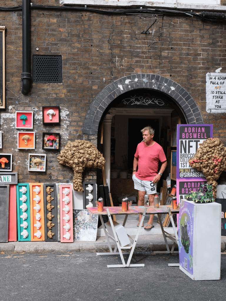Colorful art display outside brick building with a man in casual attire standing nearby.