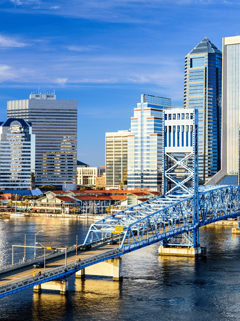 Modern skyline with city skyscrapers and a blue bridge over water in downtown.