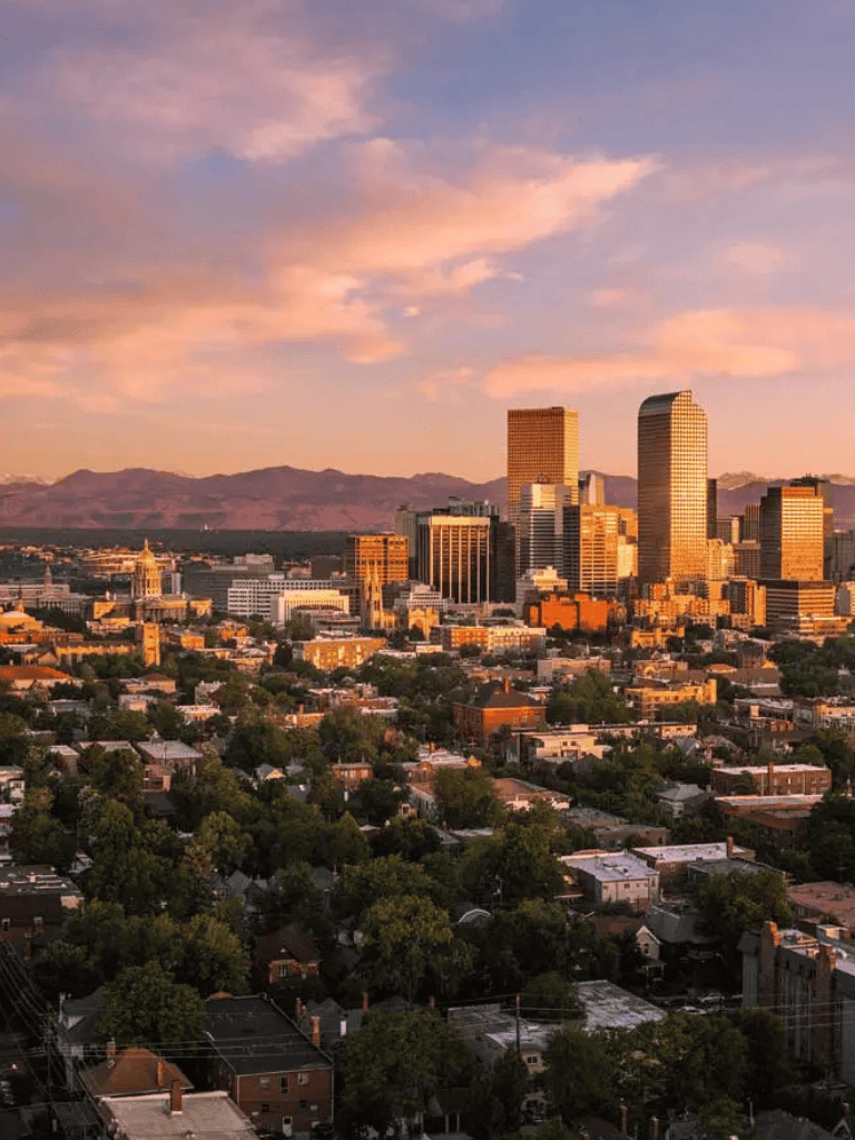 Vibrant city skyline at sunset with skyscrapers and mountain backdrop, showcasing Los Angeles urban landscape.