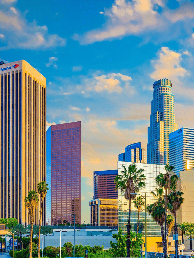 Modern downtown Los Angeles skyline with tall skyscrapers and palm trees, sunny day bright blue sky and clouds.