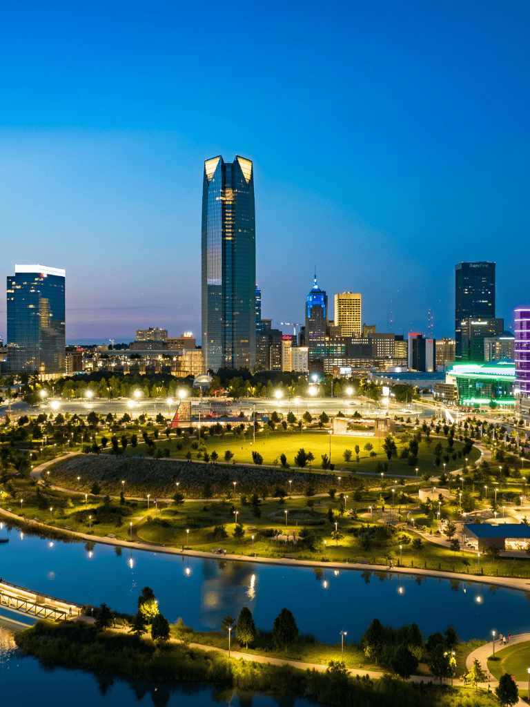 Downtown Oklahoma City skyline with park and river at dusk, vibrant cityscape, QuestForDirections guide.
